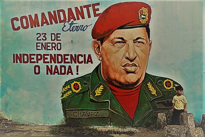 A child stands in front of a mural depicting late Venezuelan President Hugo Chavez in Caracas
