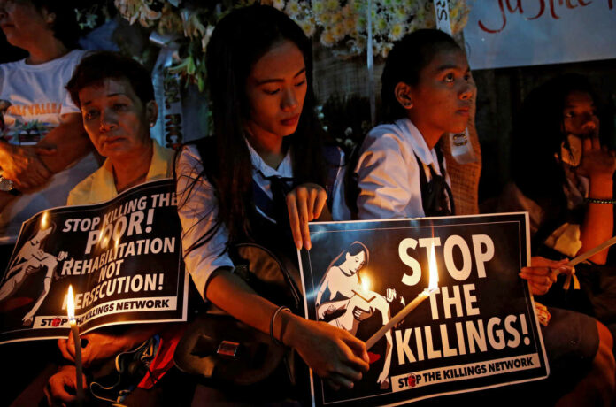 Protesters and residents hold lighted candles and placards at the wake of Kian Loyd delos Santos, a 17-year-old high school student, who was among the people shot dead last week in Manila